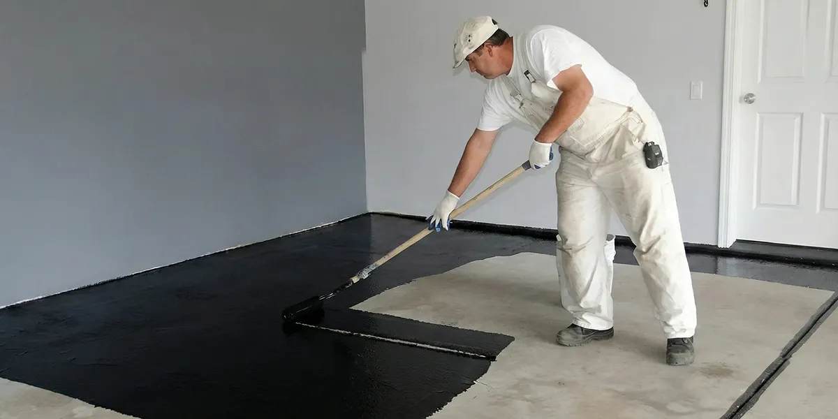 basement waterproofing professional applying waterproof coating to protect a basement floor in Columbia, MO